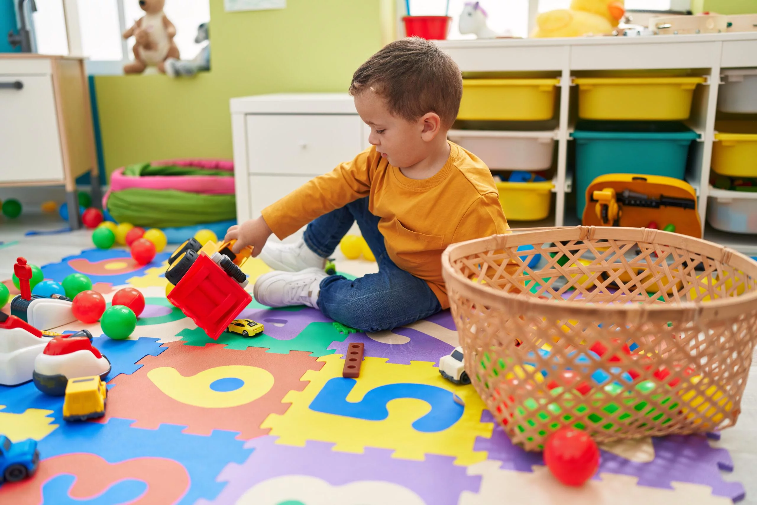 Adorable Caucasian Boy Playing With Tractor Toy Sitting On Floor At Kindergarten Adorable Caucasian Boy Playing With Tractor Toy Sitting On Floor At Kindergarten